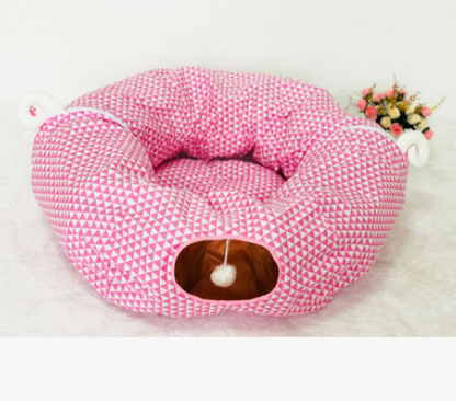 Pink geometric cat tunnel bed with oval side opening and hanging white pom-pom