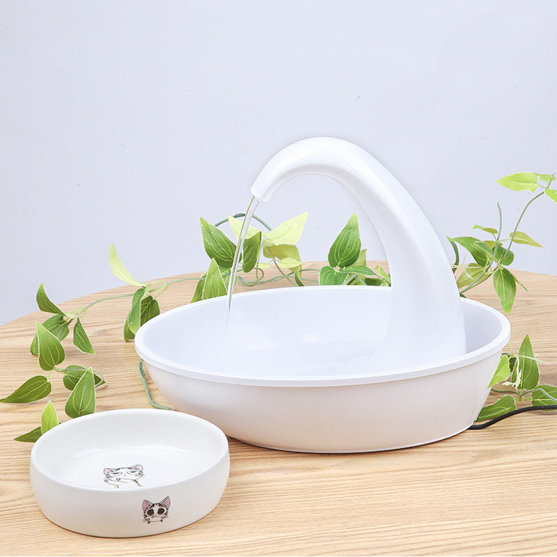 White automatic pet water dispenser bowl with curved spout on wooden surface