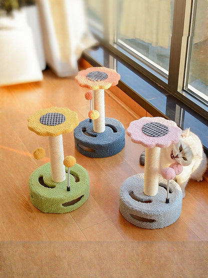 Set of three cat scratching posts with dangling balls: gray, pink, and green platforms.