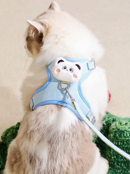 Light blue pet harness with plush bear face patch and leash, worn on a white cat