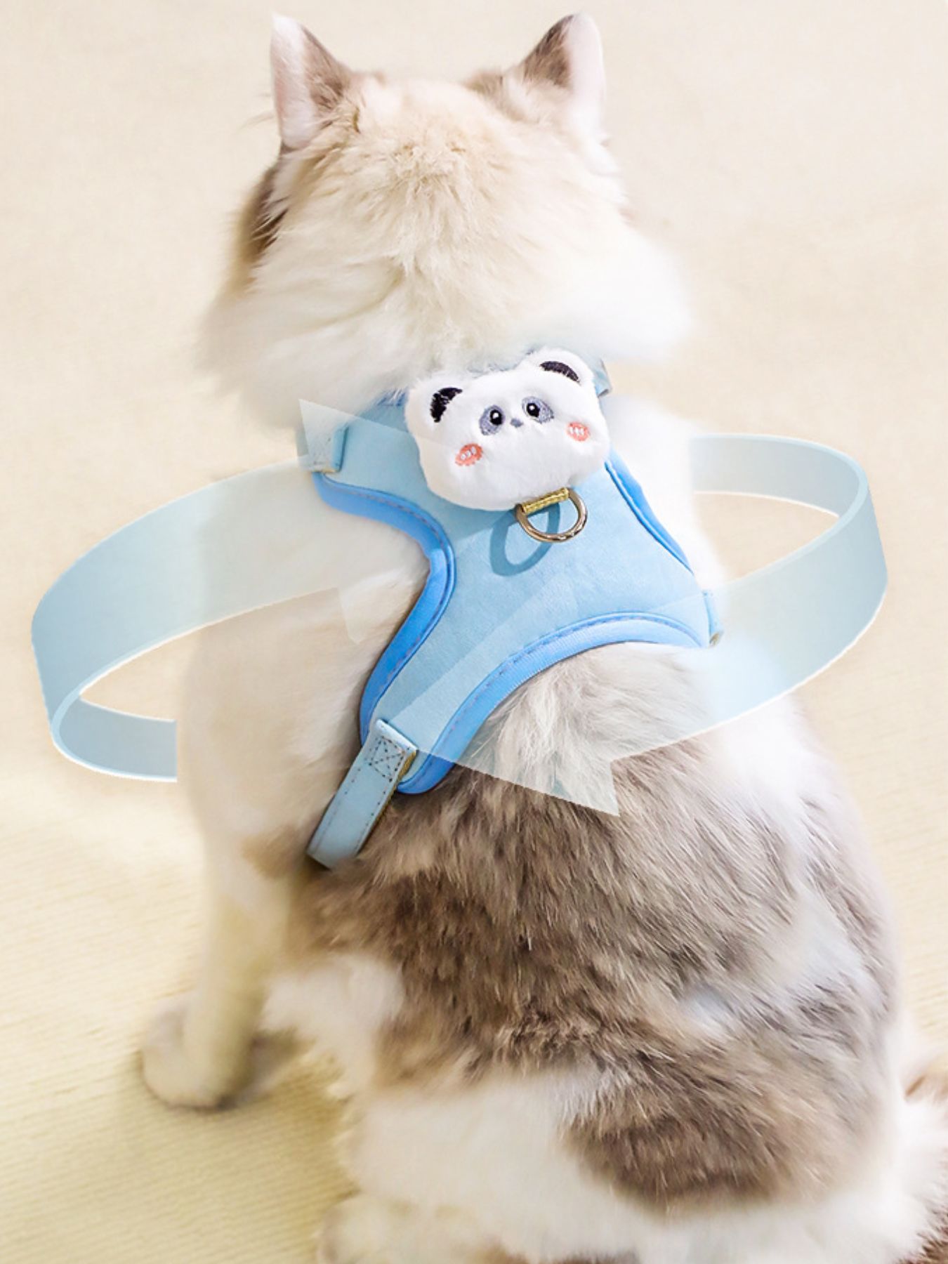 Light blue pet harness with plush bear face patch and adjustable straps, on a cat