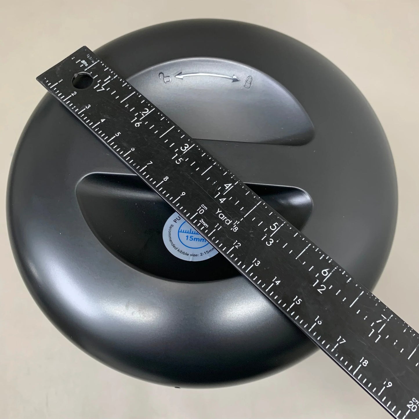 Black automatic cat feeder top with measuring tape across