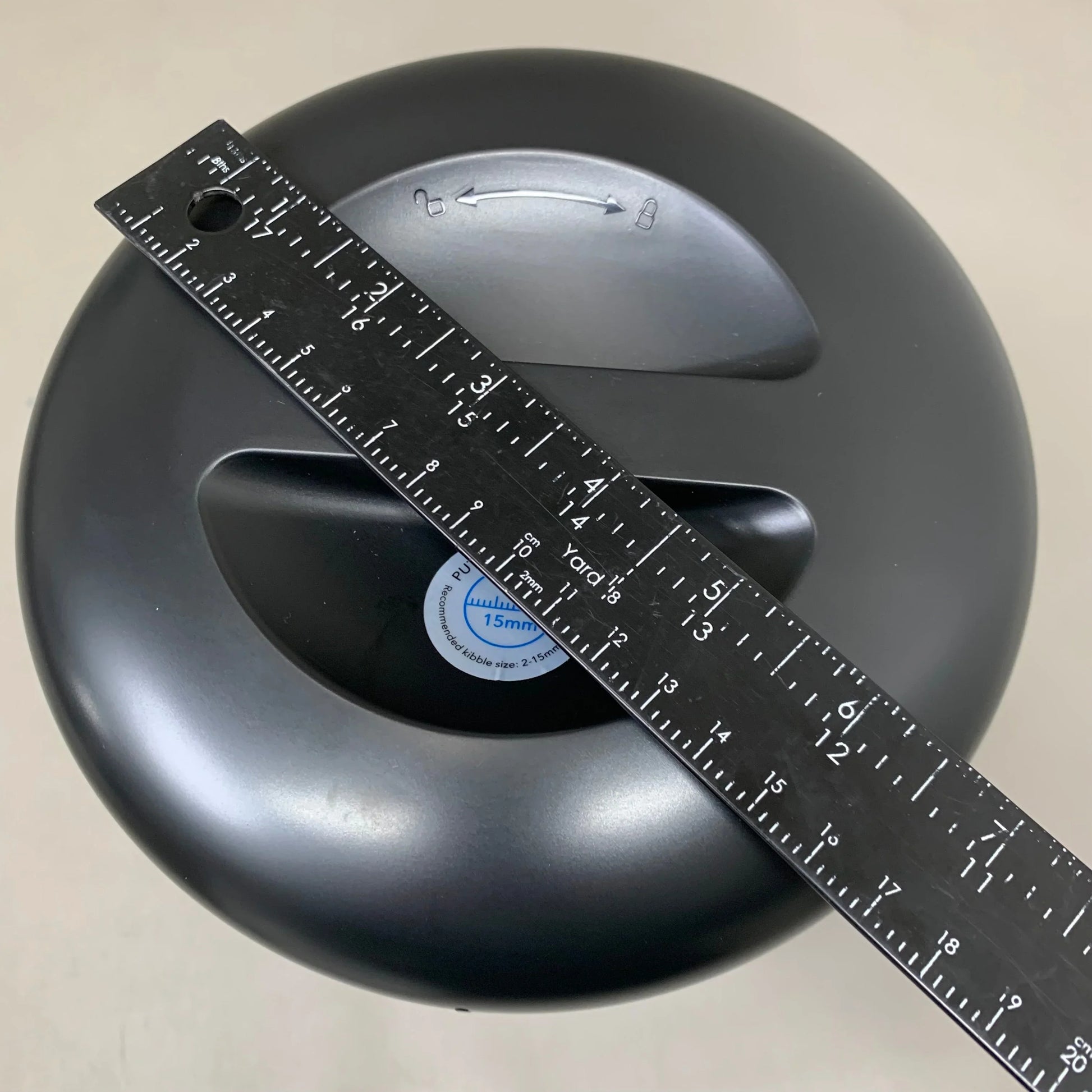 Black automatic cat feeder top with measuring tape across