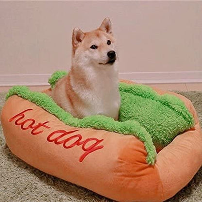 Hot dog shaped pet bed with orange cushion and green plush top; red hot dog lettering