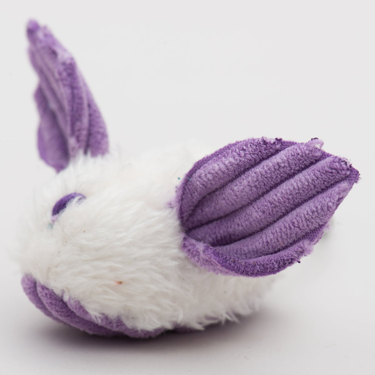Close-up of purple and white plush dust bunny cat toy with ridged ears