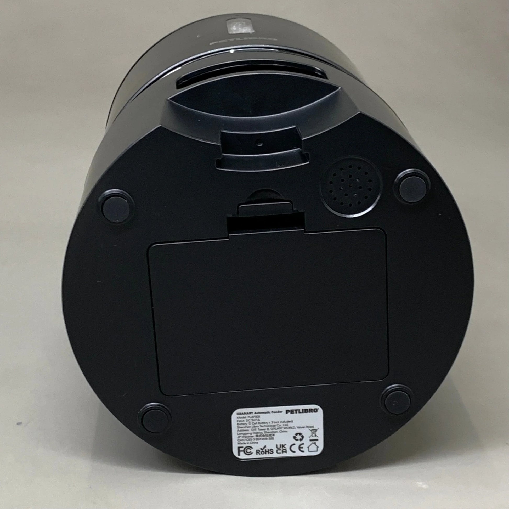 Black automatic cat feeder underside with vented speaker grille and access panel