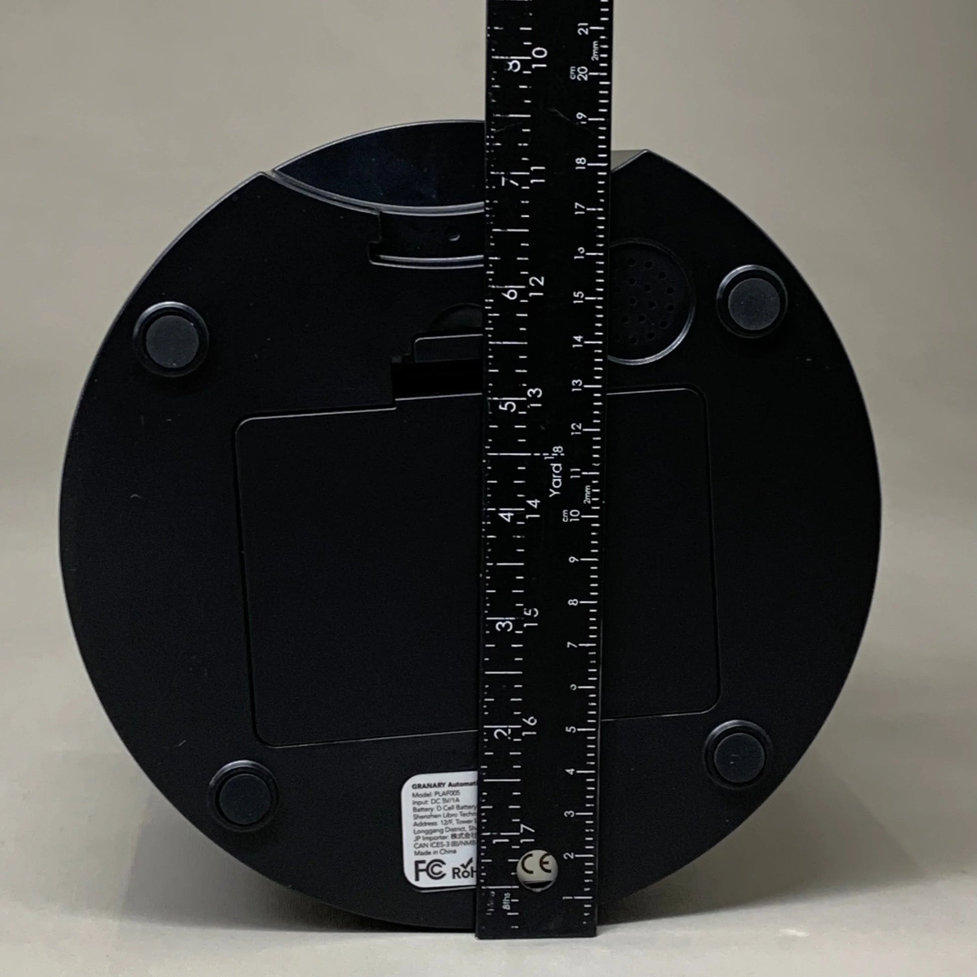 Black automatic cat feeder base with measuring tape across