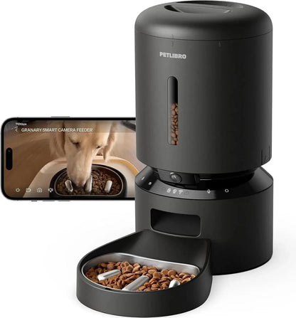 Black automatic pet feeder with camera feed on phone screen and open tray