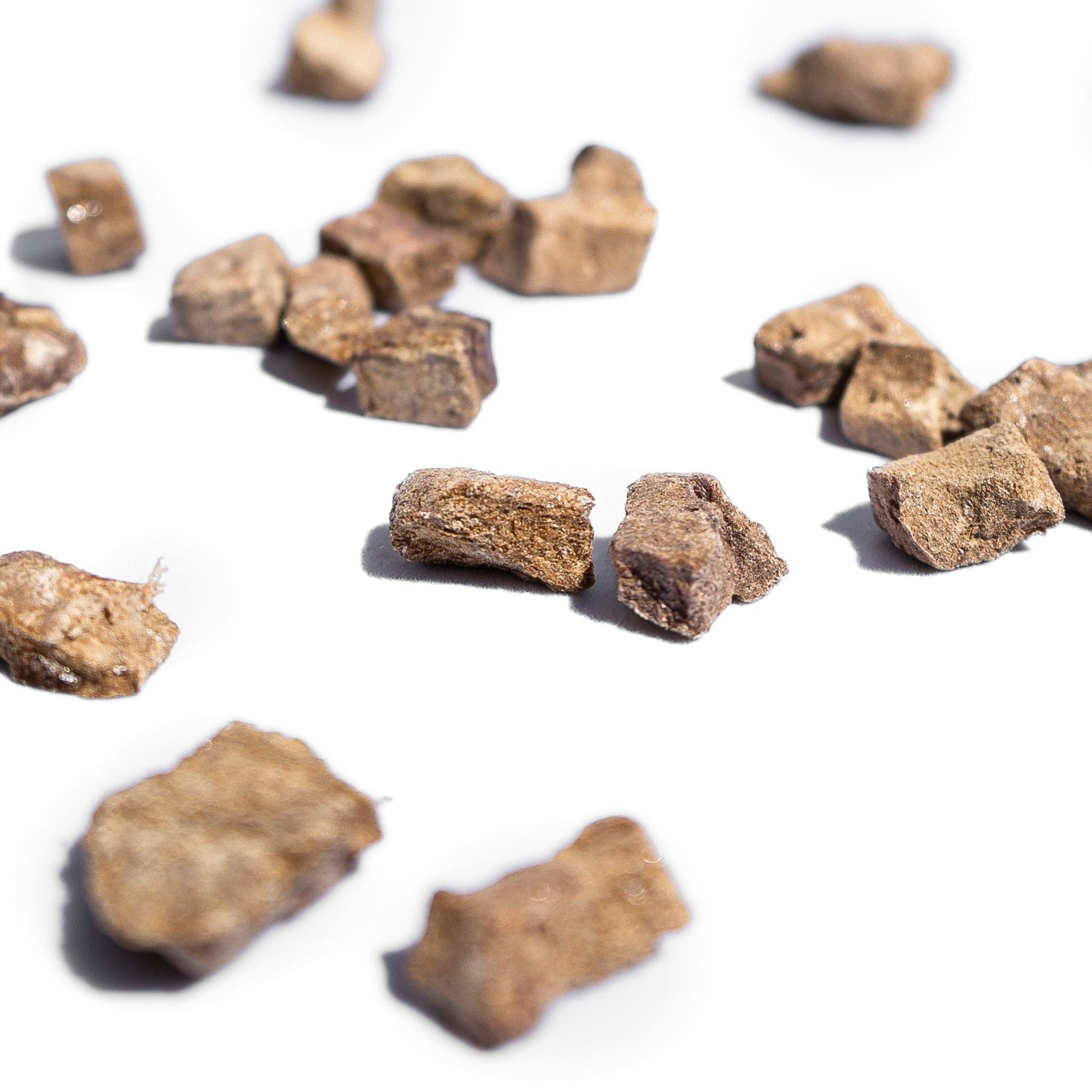 Freeze-dried beef liver dog treat pieces, scattered and irregularly shaped