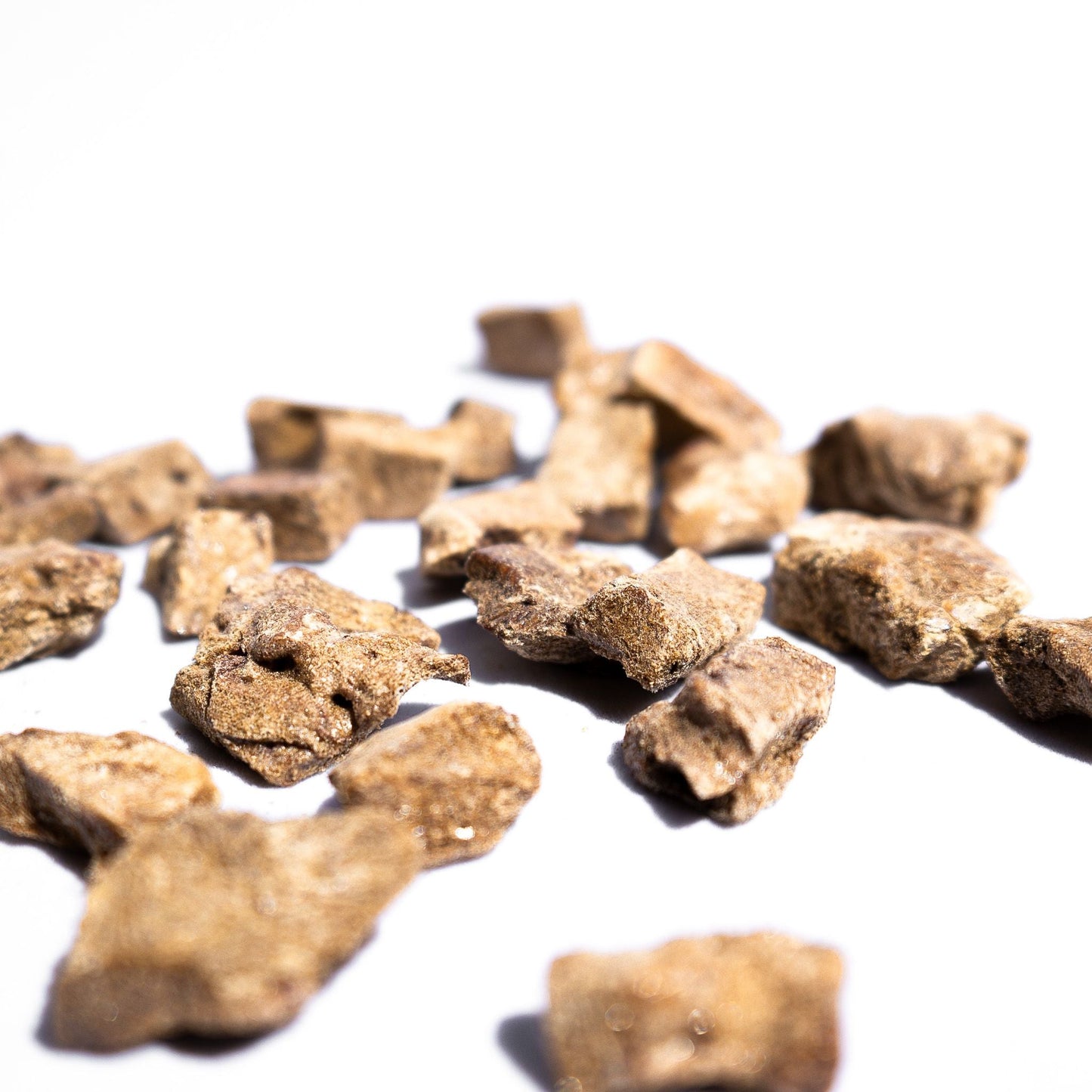 Freeze-dried beef liver dog treat chunks in a scattered pile