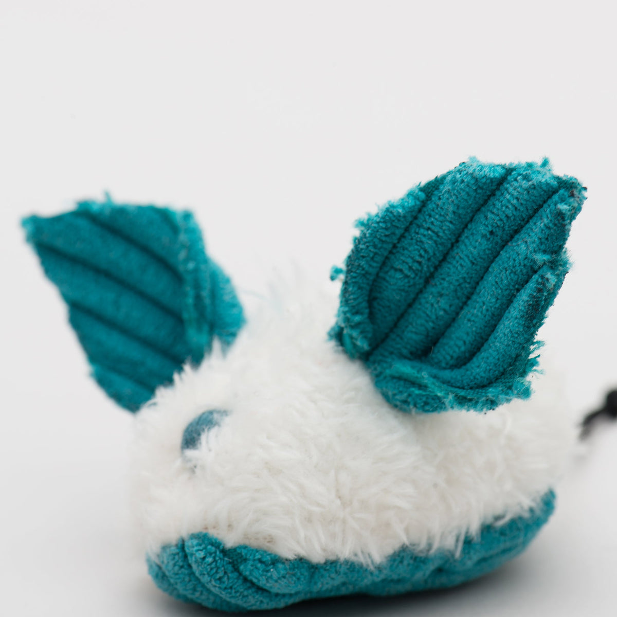 Close-up of teal and white plush dust bunny cat toy with ridged ears