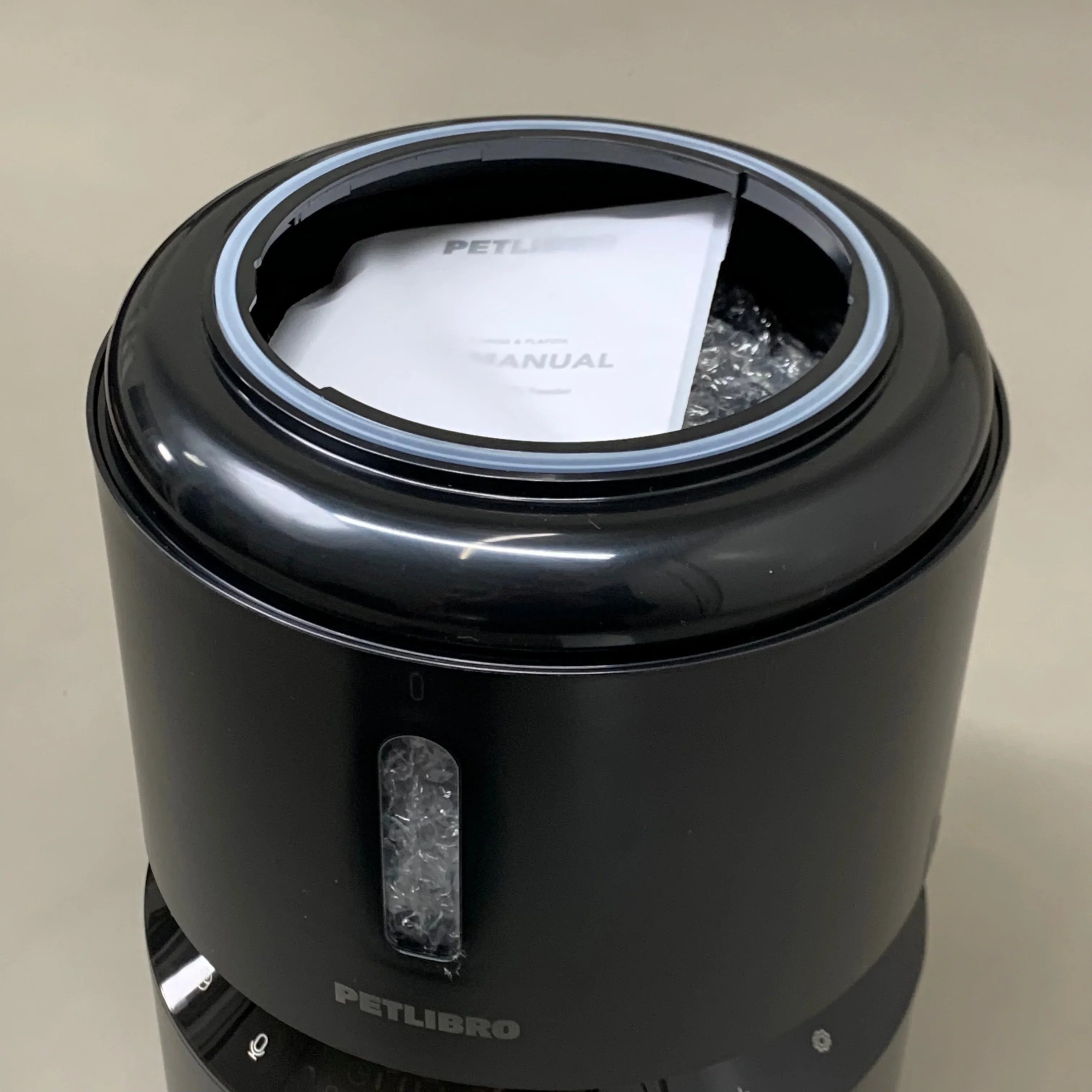 Black PETLIBRO pet water fountain with manual inside, featuring hydration for cats and dogs