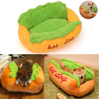 Hot dog shaped pet bed with green plush top and orange base; dog resting inside