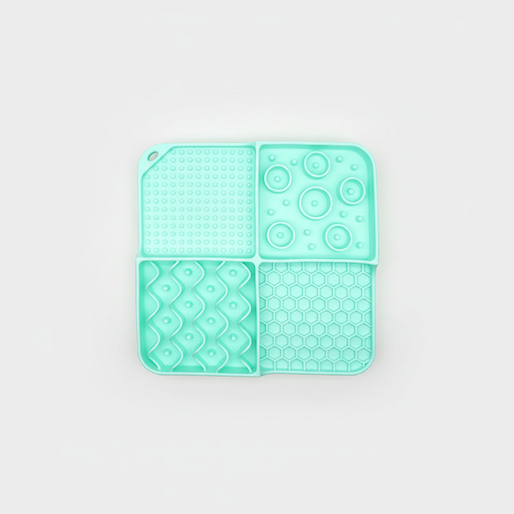 Mint silicone slow feeder lick mat in four sections with dot, swirl, and honeycomb textures