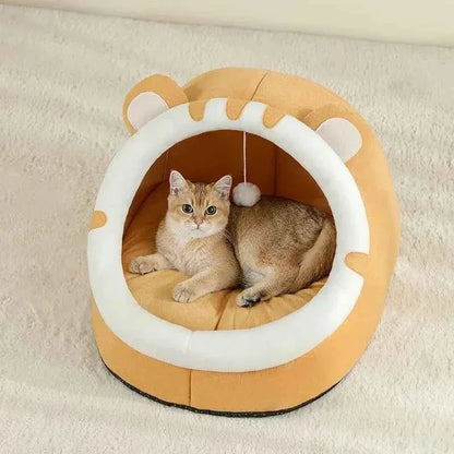 A ginger cat resting inside a WTN Essentials Cozy Cave Cat Bed shaped like a tiger face.