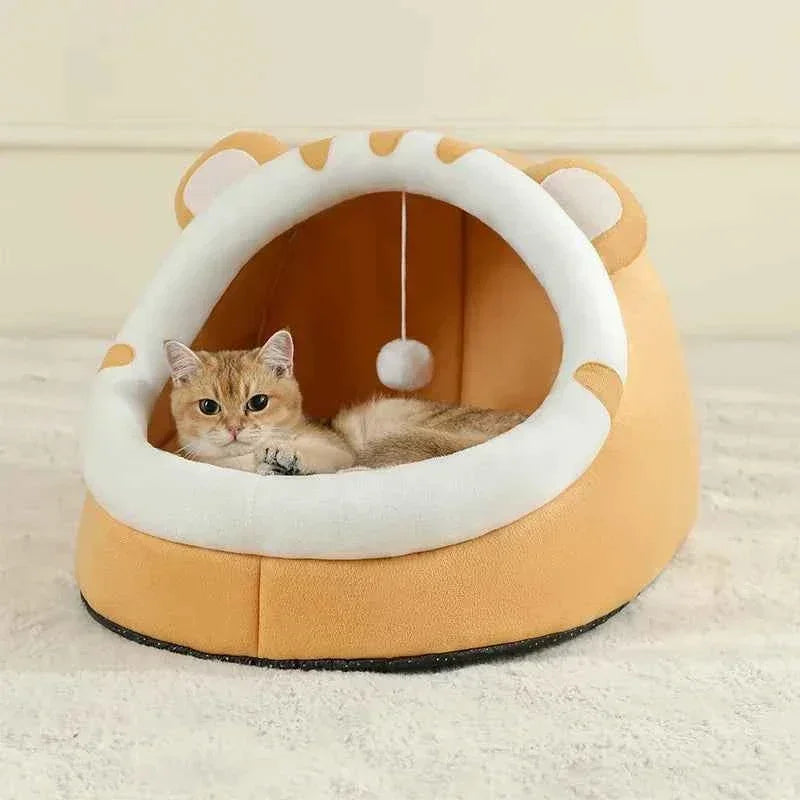 Ginger cat resting inside a WTN Essentials Cozy Cave Cat Bed with a hanging toy