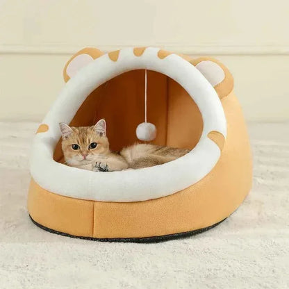 Ginger cat resting inside a WTN Essentials Cozy Cave Cat Bed with a hanging toy