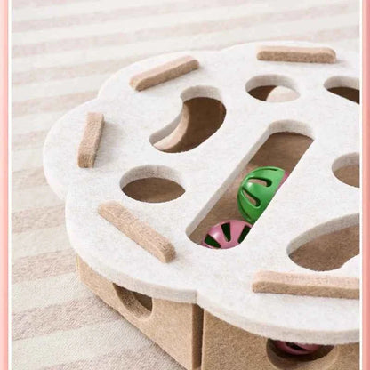 Interactive cat puzzle scratch toy with white felt top and visible ball through side opening