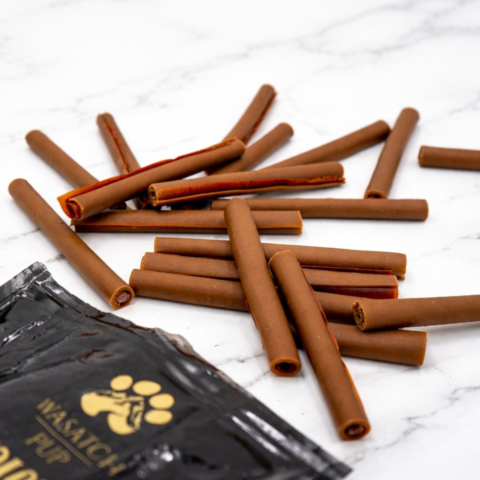 Pile of brown dog chew sticks with pouch partially visible