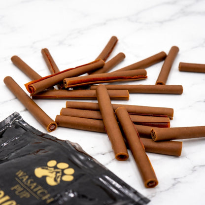 Pile of brown dog chew sticks with pouch partially visible