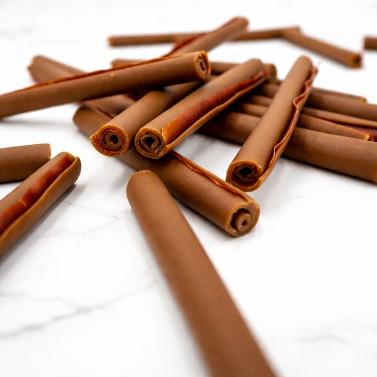 Close-up of brown rolled dog chew sticks with curled ends