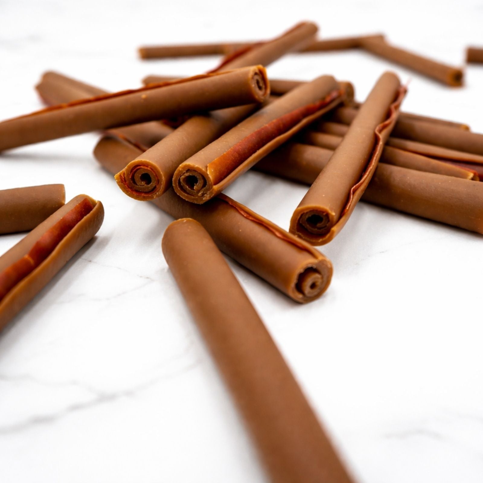Close-up of brown rolled dog chew sticks with curled ends