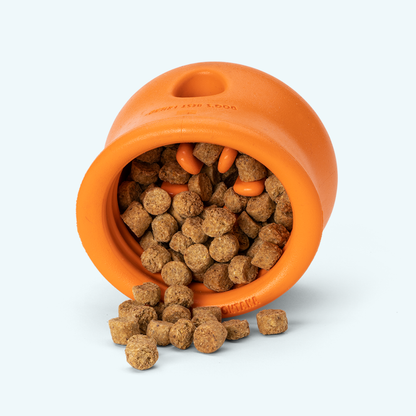 Orange silicone dog treat toy bowl filled with kibble-style treats