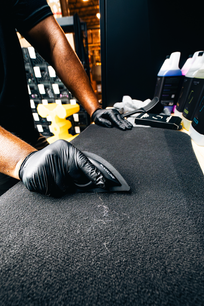 Pet grooming brush being used on grooming mat with black bristles