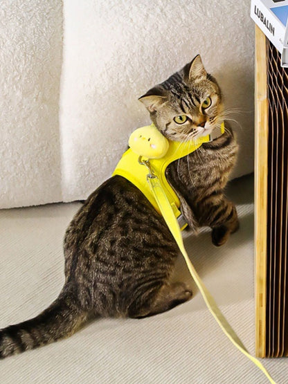 Yellow pet harness with plush animal head patch and leash, worn on a tabby cat