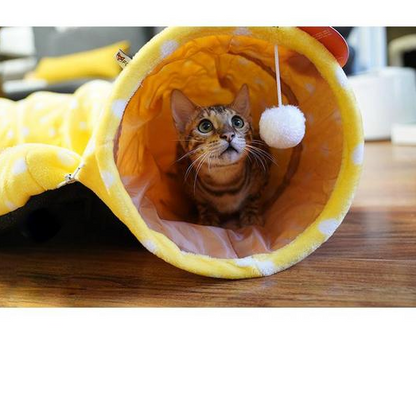 Pink plush cat tunnel bed with circular entrance and hanging white pom-pom