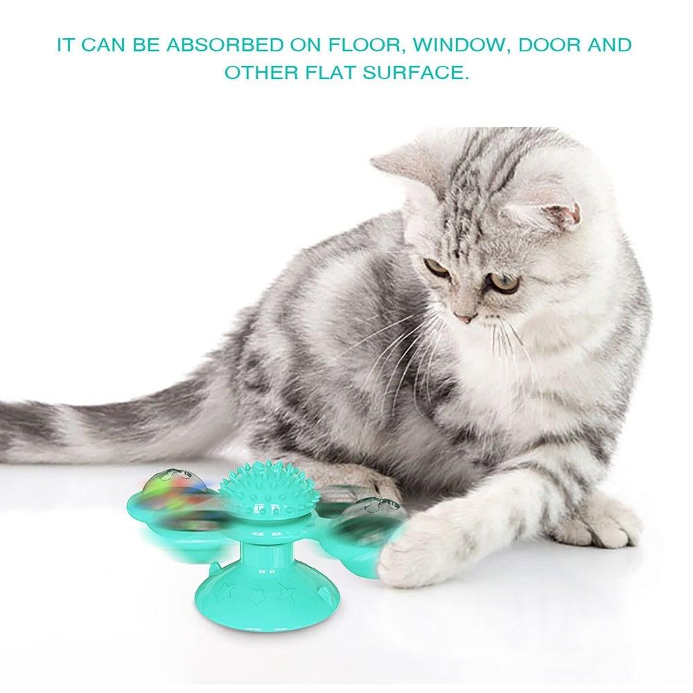 Cat windmill toy on floor with teal spiky pad and two rotating domed side cups