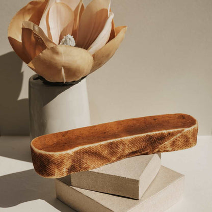 Single long brown yak milk cheese chew on a white tray