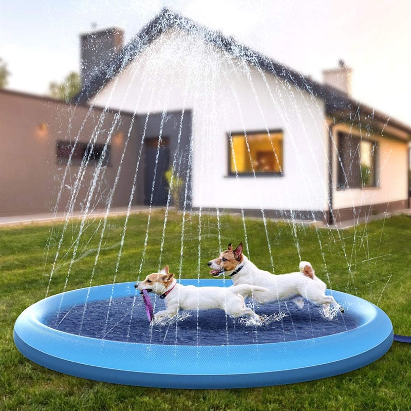 Blue round inflatable sprinkler cooling mat spraying water over two dogs in a yard