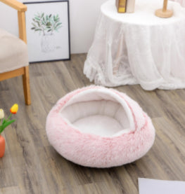 Pink oval plush pet bed with padded interior and fluffy outer edge