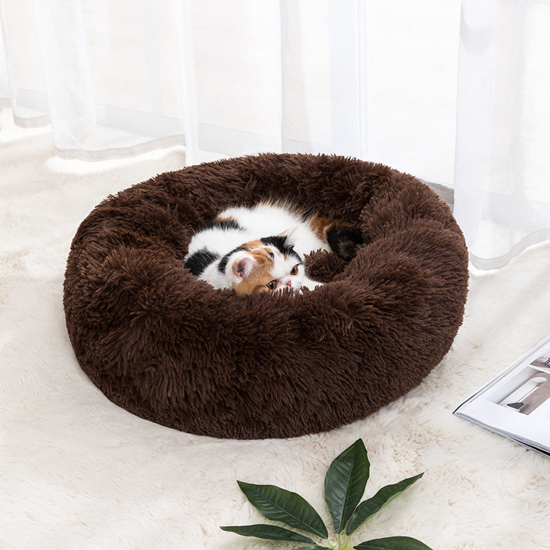 Plush round donut pet bed in brown, with a small cat curled inside.