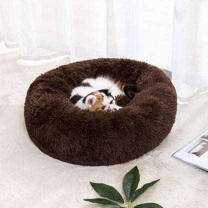 Plush round donut pet bed in brown, with a small cat curled inside.