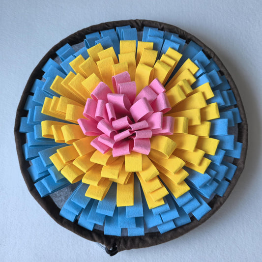 Round dog snuffle mat with blue, yellow and pink fabric strips, black rim