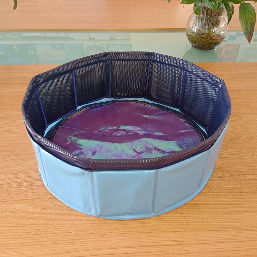 Blue collapsible PVC pet pool with dark blue rim, filled with shallow purple water