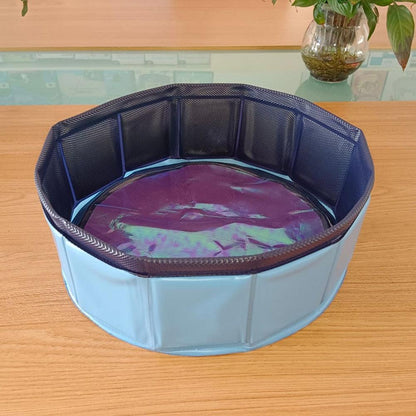 Blue collapsible PVC pet pool with dark blue rim, filled with shallow purple water