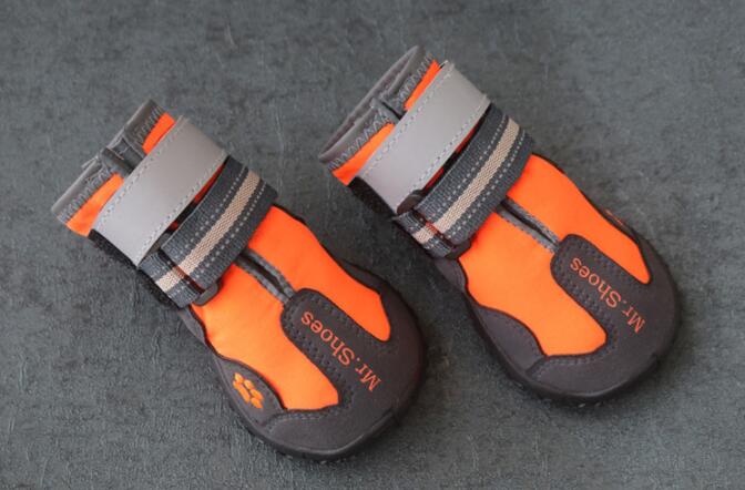 Orange and black dog waterproof booties laid on gray floor