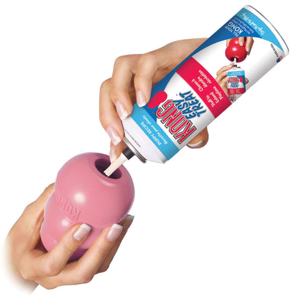 Pink KONG Puppy treat-stuffing chew toy with hands inserting a treat
